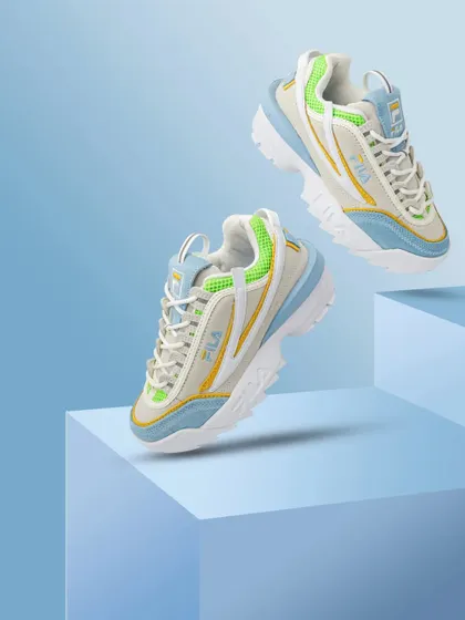 A pair of colorful Fila sneakers positioned on blue blocks, creating a playful and geometric composition.