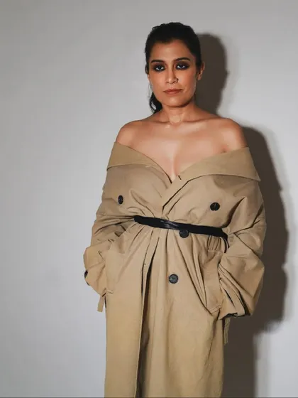 A modern, stylish portrait from a birthday celebration. The off-the-shoulder trench coat creates a chic and powerful look.