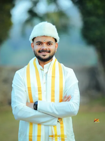 A confident portrait of the groom with his arms crossed, smiling at the camera. His traditional attire and the natural outdoor setting create a perfect pre-ceremony shot.