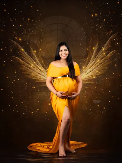 A magical, angelic portrait created with special effects. The client, in a flowing yellow gown, is given glowing wings against a dark, sparkling backdrop for a truly fantastical image.