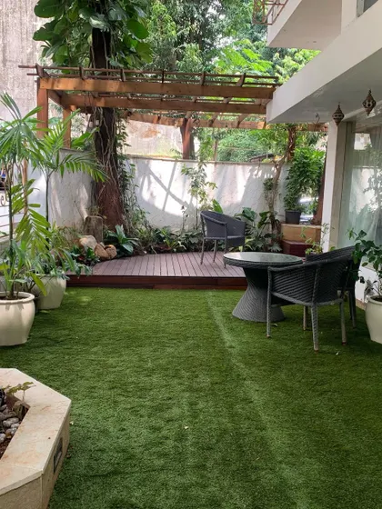 Even ground-floor spaces can become serene backyard getaways. Here, we combined a manicured lawn with a shaded wooden deck and pergola, surrounded by greenery to create a perfect spot for relaxing or entertaining.