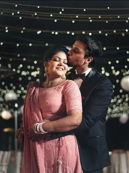 A tender kiss on the cheek under a sky of twinkling lights. This is a classic romantic shot from their wedding reception.