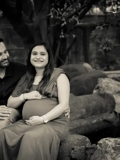 A timeless black and white portrait of an expecting couple. Seated together in a park, this image focuses on their expressions and connection, creating a classic and emotional feel.