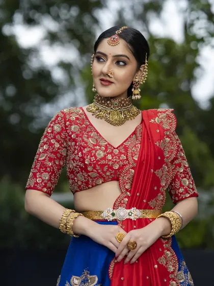 A closer look at the finely embroidered red blouse, designed to complement the royal blue lehenga. The delicate gold zardosi work shows the level of detail I bring to every piece, ensuring your bridal blouse is a masterpiece in itself.