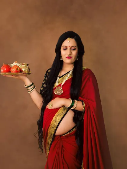 A portrait that embodies the grace and divinity of motherhood. Dressed in a traditional red saree, she holds an offering plate, reminiscent of a goddess in a temple.