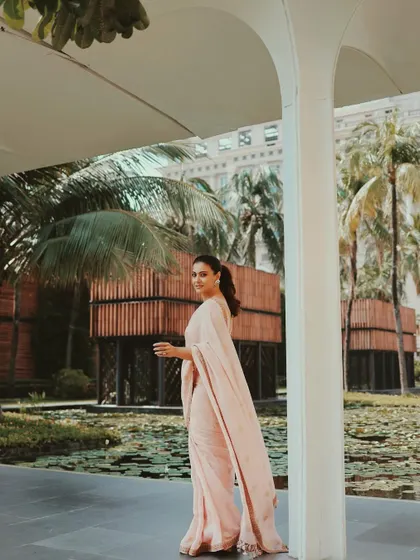 This wide shot shows the beautiful drape of the pink saree against a serene, natural backdrop. It’s a perfect example of how to look effortlessly chic and put-together.
