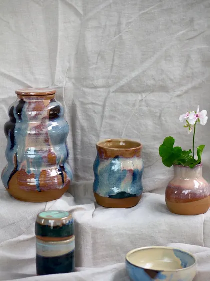 The same collection of wavy vases and bowls, with a small bud vase holding a delicate flower.
