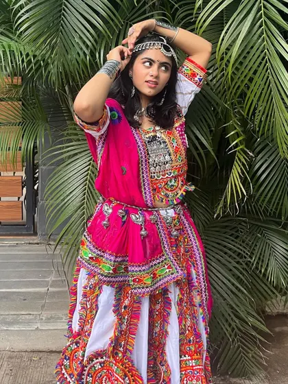 A playful pose in the white and pink outfit, showing off the matha patti and stacked silver bangles.