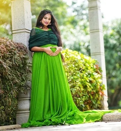 A serene moment captured during a maternity shoot. The vibrant green gown contrasts beautifully with the natural surroundings.