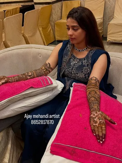 Our artists are skilled in creating detailed designs while ensuring the client is relaxed. This photo shows the full bridal mehndi application in progress during a home ceremony.