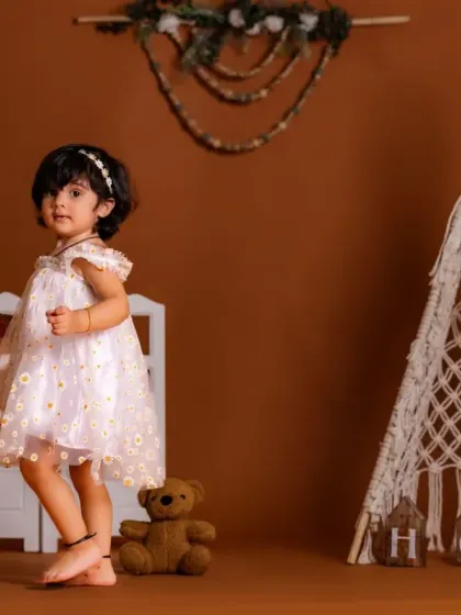 A little girl in a lovely dress standing next to our macrame teepee, a key element of our boho theme.