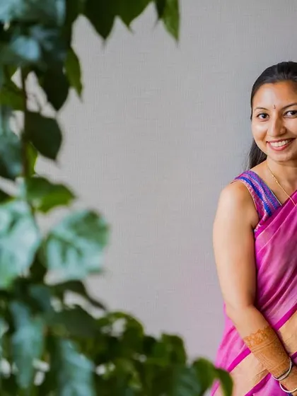 A lovely, smiling portrait of the bride, framed by green leaves, capturing her natural beauty and happiness.