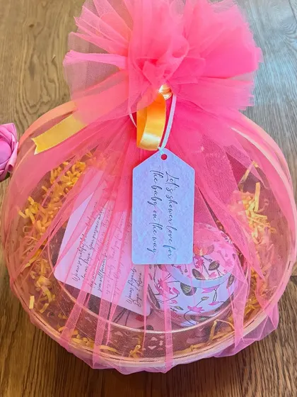 Another beautifully wrapped return gift basket, this one with a tag that reads "Let's shower love for the baby on the way." It's a sweet touch for a baby shower celebration.
