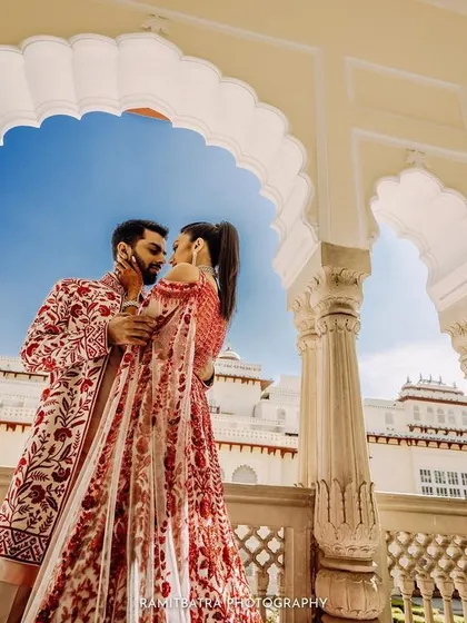 A romantic moment between the couple framed perfectly by the scalloped arches of Rambagh Palace.