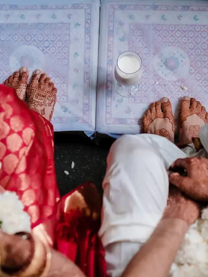 An overhead view of a couple's hands and feet during a traditional South Indian wedding ritual, showcasing the intricate customs involved.