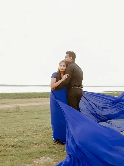This wide shot shows the full effect of the royal blue trail gown against the open landscape. It's a perfect choice for couples wanting epic pre-wedding photos.