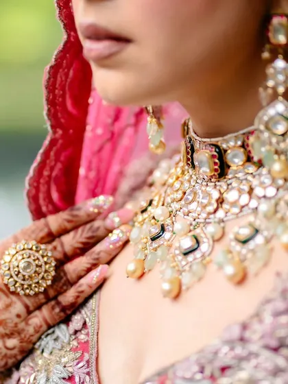 A detailed shot of the bride's necklace and the mehendi on her fingers.