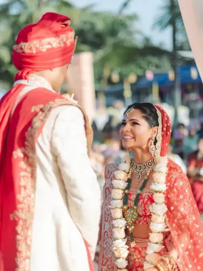 A classic first look shot, capturing the bride's adoring gaze as she stands before her groom. The golden hour light at their Goa wedding adds a warm, romantic glow.