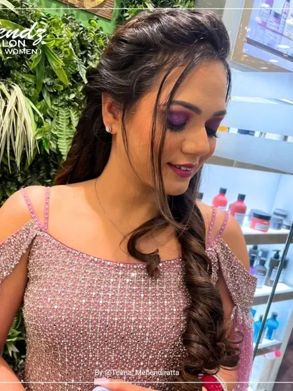 A side profile showing the beautiful blend of the purple eyeshadow and the soft curls of her hairstyle. This angle highlights the seamless finish of the makeup.