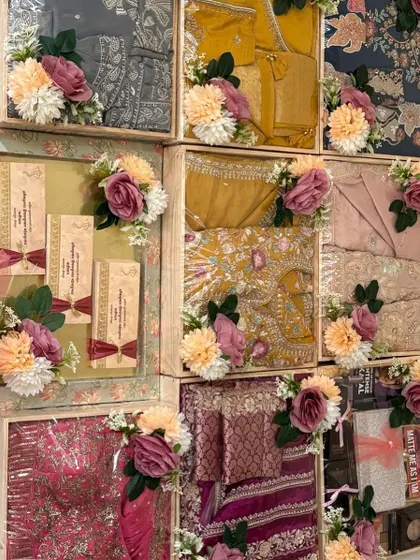 An assortment of wedding gifts, each packed in its own custom-decorated pinewood tray. The display includes traditional wear, personalized invitation cards, and other thoughtful presents.