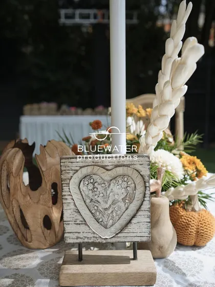 A simple centerpiece with a carved wooden heart, reflecting the rustic and romantic theme of the event.