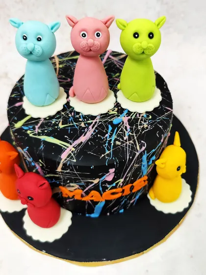 We play with color and art in this modern cat-themed cake. A dramatic black cake with neon paint splatters serves as the canvas for a parade of colorful, stylized cat figures, making it a unique and artistic choice for a cat lover.