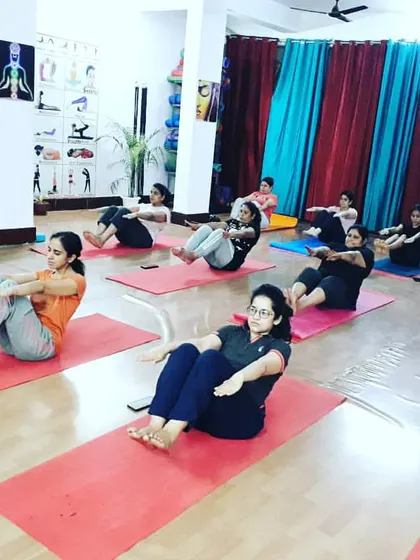 Students building core strength with Ardha Navasana (Half Boat Pose). A strong core is the foundation for many advanced yoga postures.
