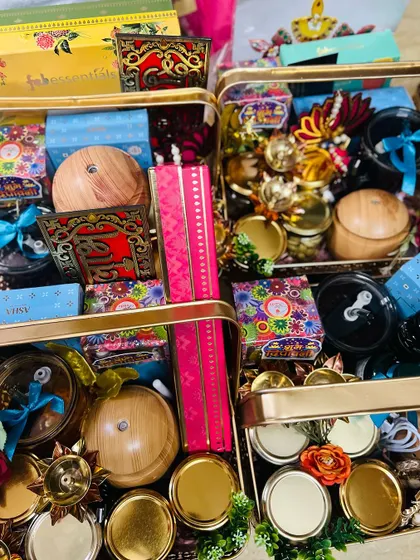 A top-down view of multiple Diwali hampers being prepared, showing the variety of items like diffusers, sweets, and decorative boxes that can be included.