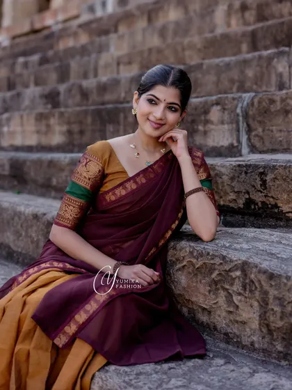A moment of rest during a temple shoot, wearing a mustard and maroon half-saree. The soft light and relaxed pose offer a different perspective on this traditional outfit.