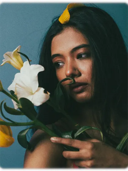 A pensive and beautiful portrait with the model holding flowers close to her face.