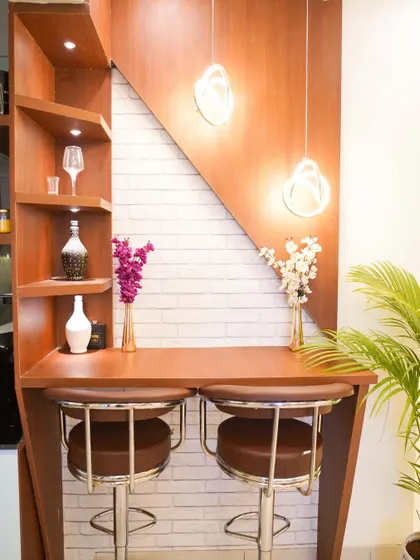 A close-up of the stylish breakfast counter, featuring a wood-finish top, a white brick accent wall, and elegant shelving for display.