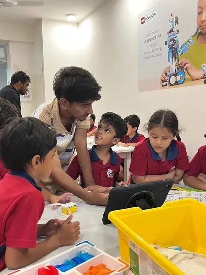 An instructor at Vidyashilp Academy engages with a group of students, using a tablet to explain a concept and answer their questions.