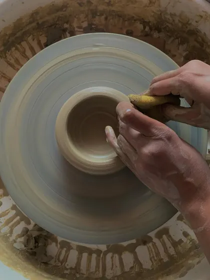 Using a sponge to smooth the rim of a freshly thrown bowl. This simple action makes the piece more comfortable to use and gives it a refined, finished quality.
