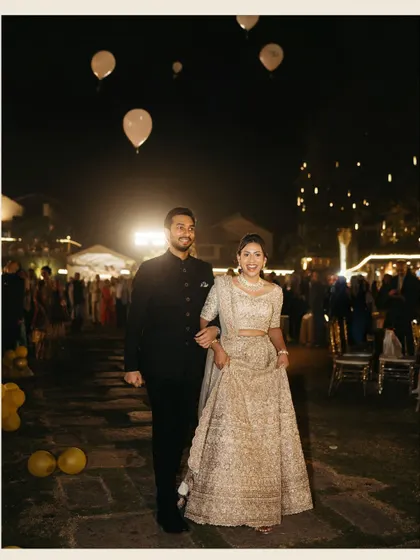 The couple makes their grand entrance at the reception, walking under a sky of white balloons. A moment of pure celebration and joy.