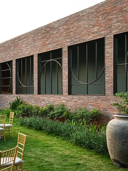 A distinctive feature of Samavana is the brick wall with large, custom-designed windows featuring geometric metalwork. This detail adds an artistic, contemporary touch to the otherwise rustic material palette.