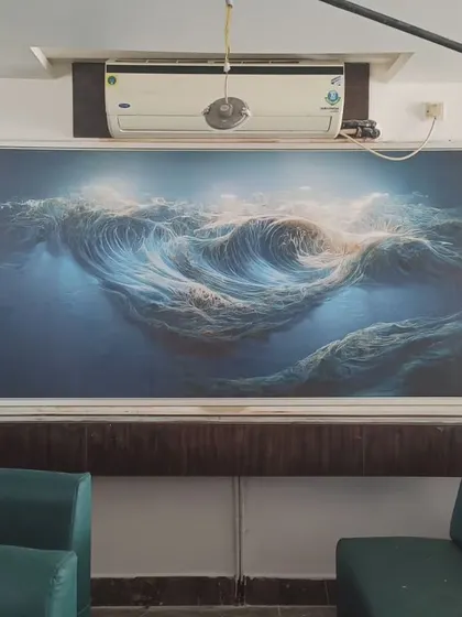 An abstract mural depicting ocean waves, framed and mounted on the wall. The swirling blues create a powerful sense of motion.