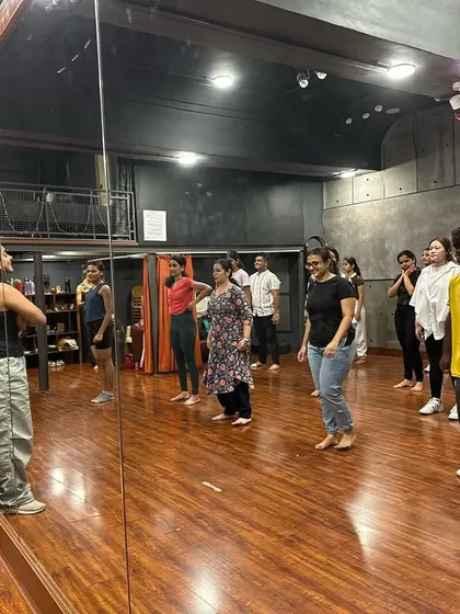 A mirror-view of the class, showing students learning and practicing together. The studio's mirrored walls are essential for self-correction and learning.