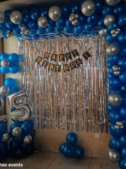Another view of the blue and silver 25th birthday wall decoration. The balloon frame and shimmer curtain create a great photo booth area.
