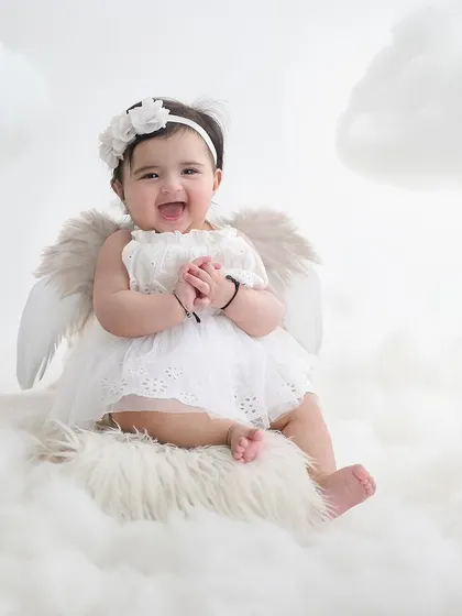 An angel sitting on a cloud. We use simple, elegant props and soft textures to create heavenly portraits that feel pure and timeless.