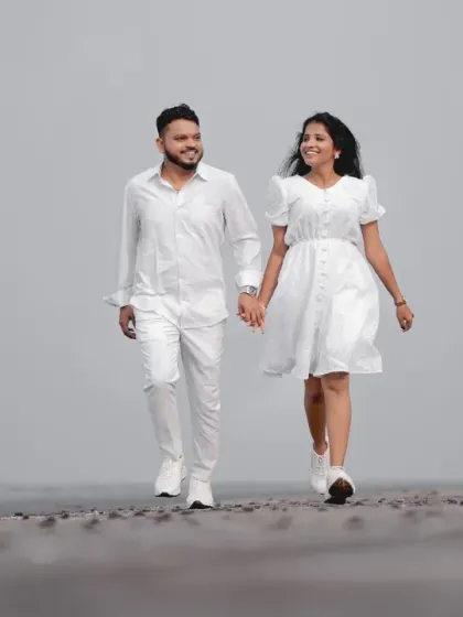 A minimalist pre-wedding photo of a couple in all-white outfits, walking hand-in-hand. This clean and simple composition focuses entirely on their connection.