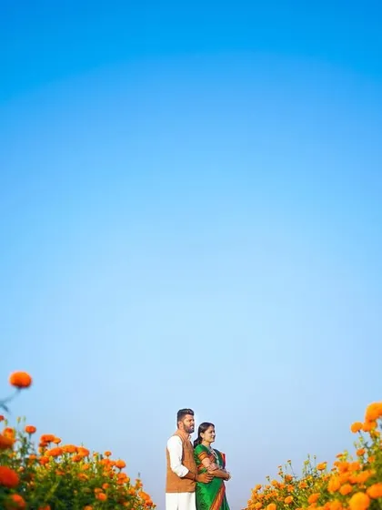 Using the vast blue sky and the vibrant orange of the marigold field to frame the couple. This wide-angle shot creates a sense of scale and beauty, making the couple the central focus in a breathtaking landscape.