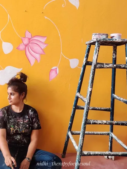 Taking a moment during the painting of the Pichwai-inspired Scrabble wall. You can see the initial white base coats for the lotus flowers and buds on the vibrant yellow wall.