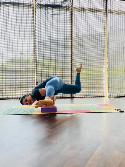 A student using a block for support in a challenging arm balance. Props are not a sign of weakness; they are tools for intelligent practice.