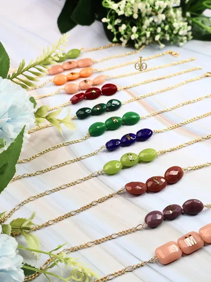 The full color range of our oval-shaped semi-precious stone Rakhis, each ready to be personalized with an initial.
