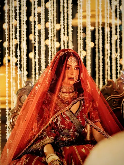 A beautiful shot of the bride under her red veil, seated at the mandap, looking every bit the royal queen.
