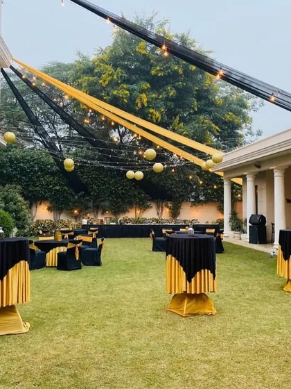 A black and gold theme exudes elegance and style. This outdoor setup includes high top cocktail tables and coordinated linens, with string lights and paper lanterns adding a warm glow for an evening networking event.