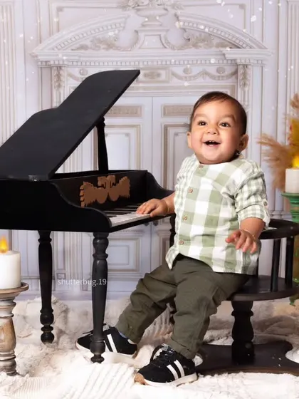 This little musician is all smiles as he sits at the piano, surrounded by warm candlelight.