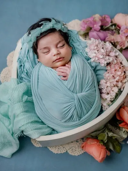 A floral dream. This baby is swaddled in soft blue and nestled in a bowl of flowers, creating a peaceful and beautiful composition.