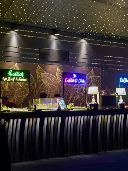 A full view of the bar under a ceiling of stars. The custom neon signs and well-lit back bar create an inviting and high-energy focal point for the evening.