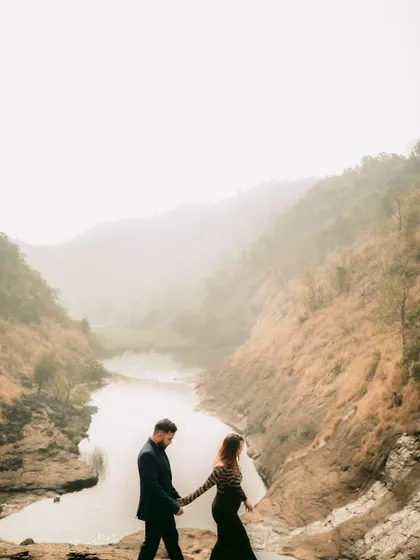A wide shot of the couple walking along a cliff, capturing the scale of the landscape and the story of their journey.